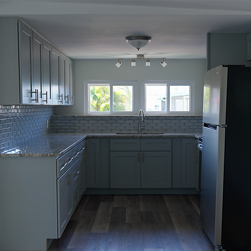 Remodeled mobile home kitchen with new cabinets, countertops, and updated lighting by Freedom Mobile Home Services.